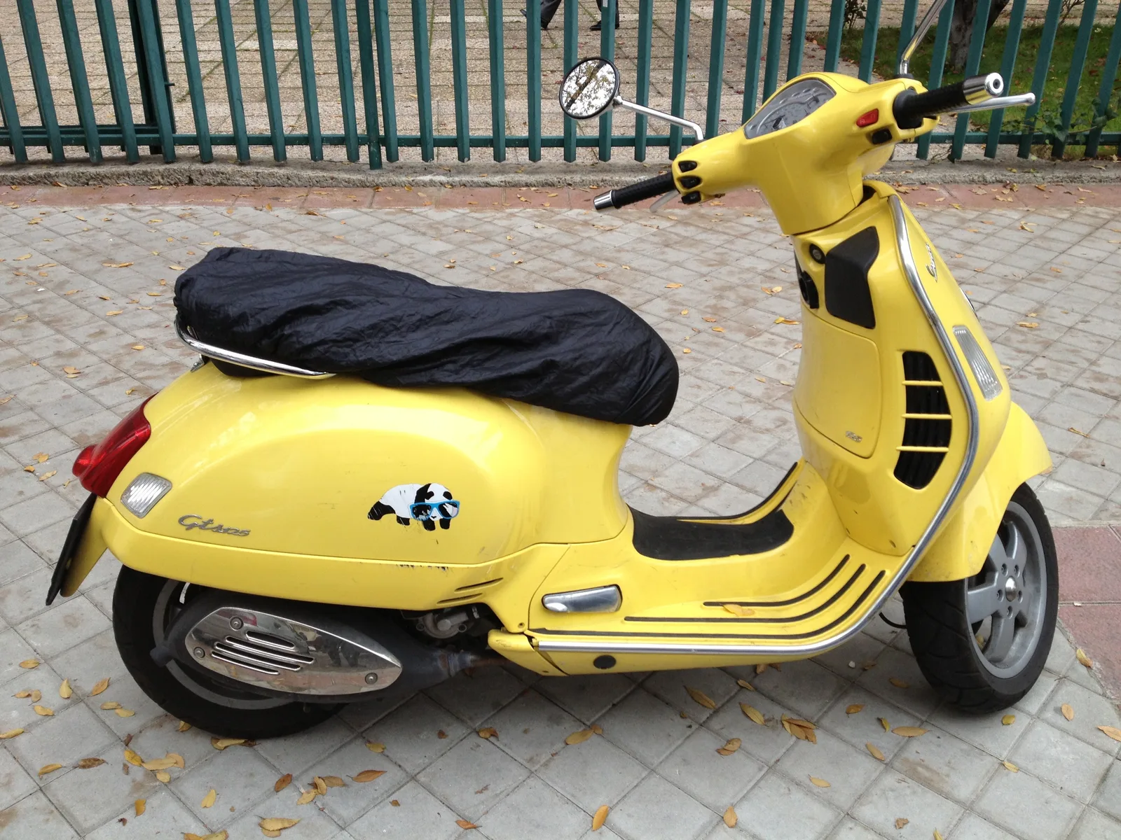 Scooter 125 amarilla aparcada en la acera de una calle