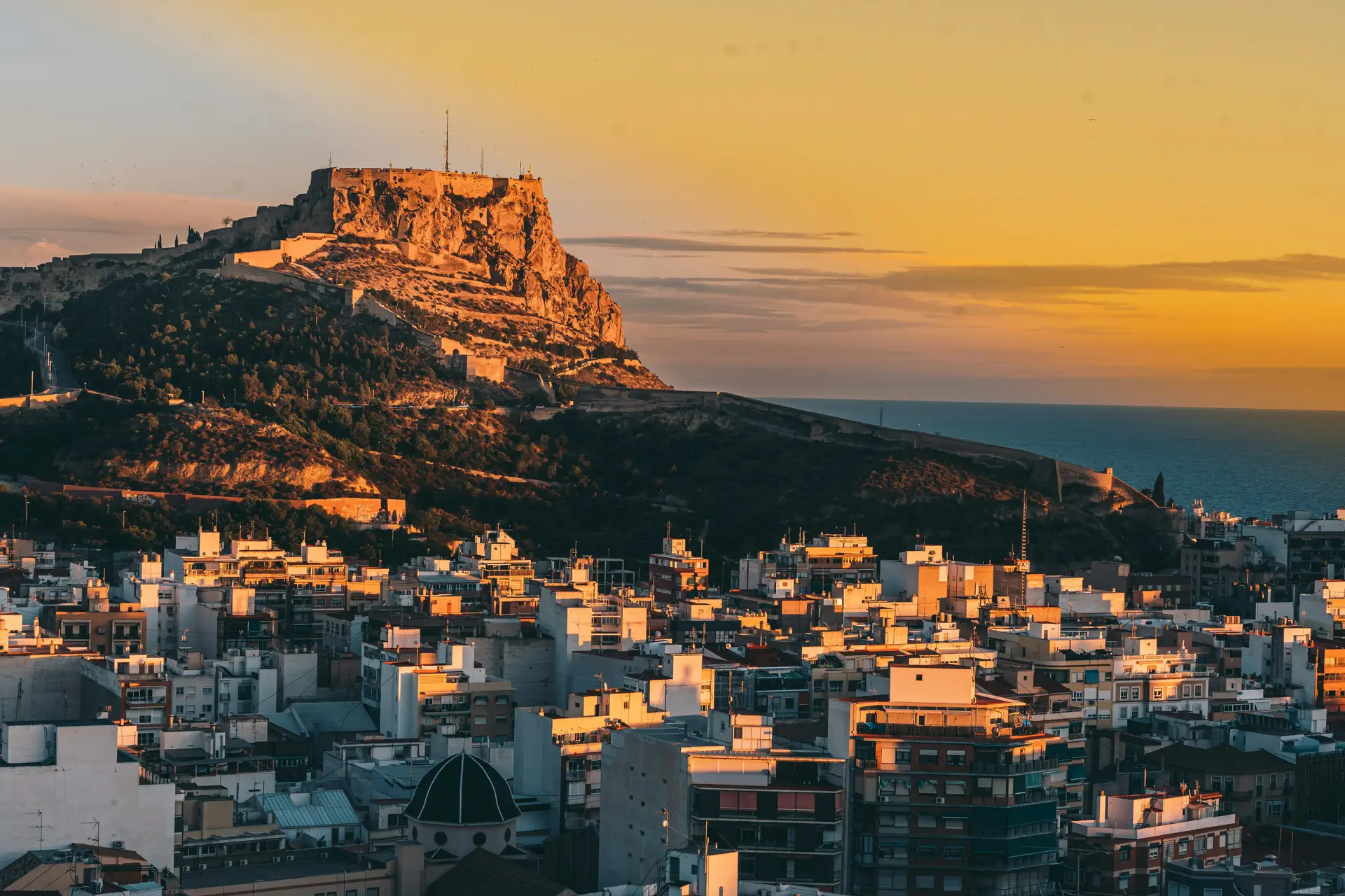 Zwarte 125cc-scooter aan de haven van Alicante bij zonsondergang